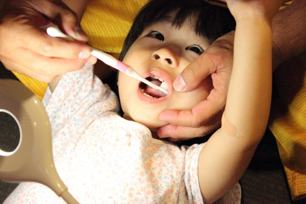 仕上げ磨きをされている子ども