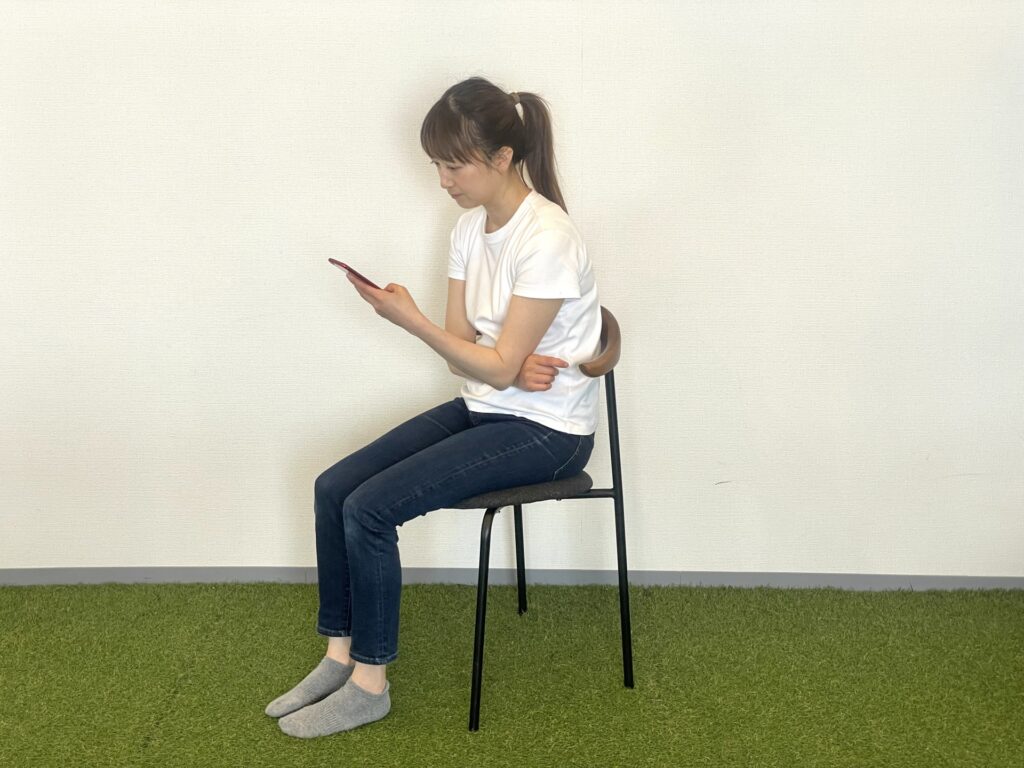 猫背でスマートフォンを操作する女性